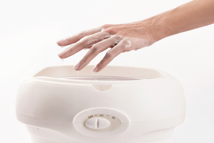 Woman in a nail salon receiving a manicure, she is bathing her hands in paraffin or wax